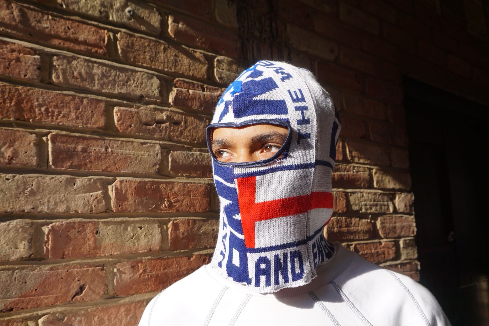 Our model wearing our England football scarf balaclava framed against a brick wall