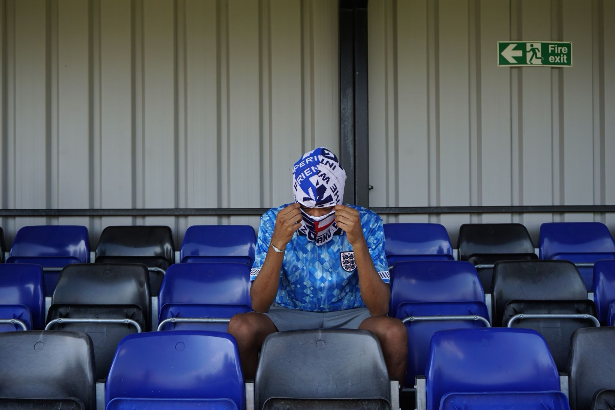 Our model wearing our England football scarf balaclava sitting in the stands at a football ground